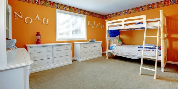 Chambre d'enfant aux murs oranges avec un lit mezzanine blanc.